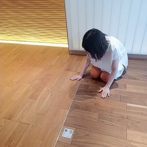 通常の天然木のフローリング（左）と、ライブナチュラル・フォー・ドッグの手ざわりの違いを確かめる。天然木の質感は全く失われていない