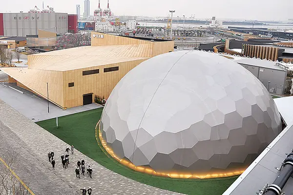 天候や時間帯で見え方が変化するタマゴ型の電力館(手前)と、約1000本の国産の木材を使った住友館(2月28日撮影)